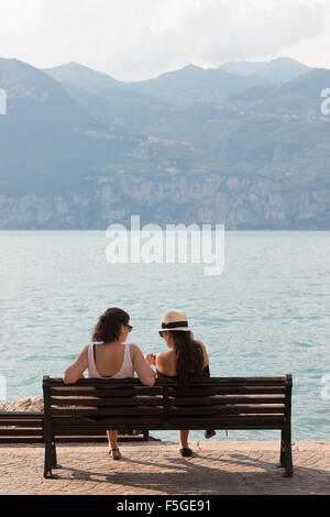 Castelletto di Brenzone, Italien, zwei junge Frauen sitzen auf einer Bank am Ufer Sees Stockfoto