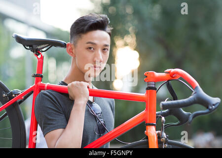 Junger Mann mit Fahrrad auf Schulter Stockfoto