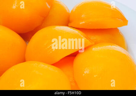 Nahaufnahme von einigen geschält und halbiert Pfirsiche in Sirup in einem weißen Teller Stockfoto