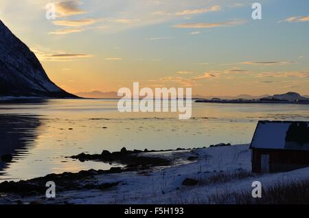 wunderschönen Fjord und lebendige farbige Himmel am Fjord mit kleinen roten Bootshaus und orange Nebel Stockfoto