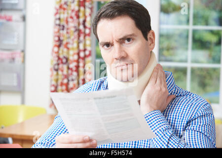 Mann liest Brief nach Erhalt Nackenverletzung Stockfoto