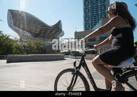 Fisch oder Peix, Gehrys Bronzeskulptur am Olympischen Hafen Zone. Sonne Badegäste am städtischen Strand von Barceloneta, Barcelona, Catalan, Spanien Stockfoto