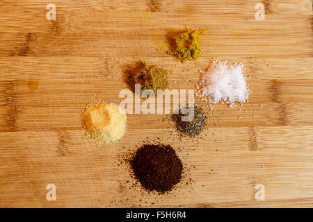 Nahaufnahme der Prisen bunte Kräuter und Gewürze in den Stapel auf Schneidebrett Stockfoto