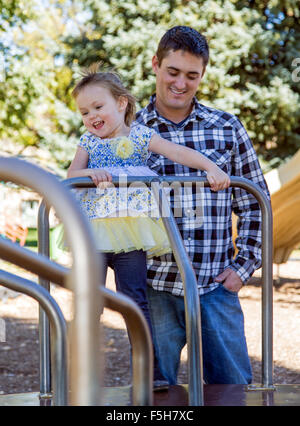 Vater und junge Tochter auf einem Karussell, sonnigen Tag, Park Spielplatz draußen spielen Stockfoto