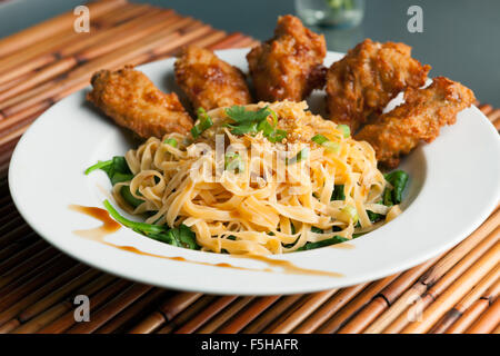 Chicken Wings mit Nudeln und Spinat Stockfoto