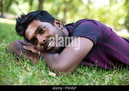 ein junger Mann liegt auf dem Rasen im park Stockfoto