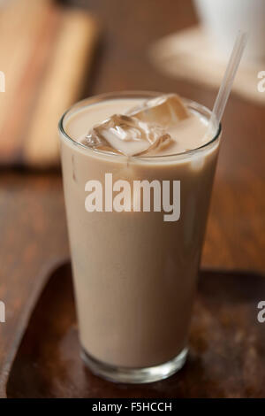 Iced Chai im Longdrinkglas mit Eis und Strohhalm auf Holz Stockfoto