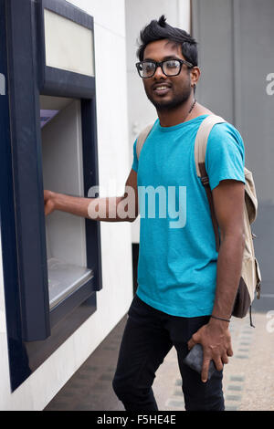 junger Mann am Geldautomaten Bargeld abheben Stockfoto
