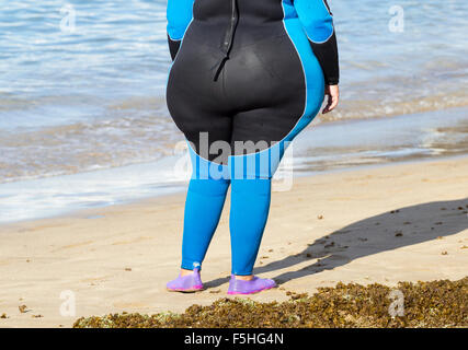 Übergewichtige Frau trägt Neoprenanzug Ar Wassersportzentrum am Strand in Spanien