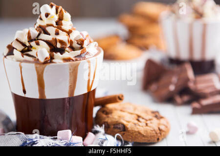 Eine unordentliche Tasse mit heißer Schokolade, Sahne, Marshmallows und Choclate Chip Cookies. Stockfoto