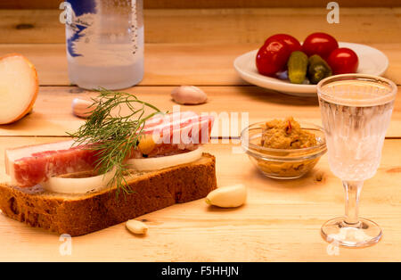 Sandwich mit gewürzte Schmalz serviert mit Knoblauch, Zwiebeln, würziger Senf, Gurken, Tomaten und Wodka Stockfoto