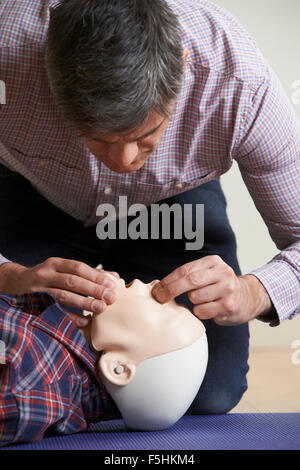 Mann In erste-Hilfe-Kurs durchführen von Mund zu Mund Beatmung auf Dummy Stockfoto