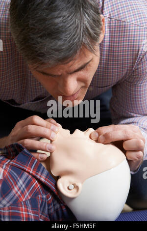 Mann In erste-Hilfe-Kurs durchführen von Mund zu Mund Beatmung auf Dummy Stockfoto