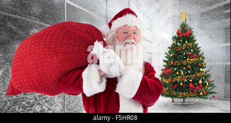 Zusammengesetztes Bild von Santa trägt seine rote Tasche und lächelt Stockfoto