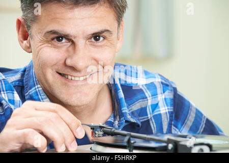 Reifer Mann, der Vinyl-Schallplatte auf Player Stockfoto