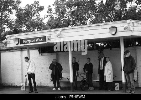 Menschen warten auf den Zug im Regen bei Hampton Wick Bahnhof Stockfoto