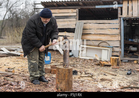 Alten ukrainischen Bauern Drechseln Holz mit einer Axt Stockfoto