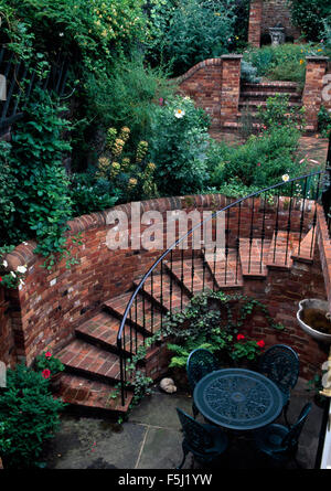 Vogelperspektive des schwarzen Metall-Tisch und Stühle auf einer versunkenen Terrasse neben Ziegel Schritte mit Metallgeländer Stockfoto