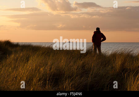 Ein Mann mit einer Kamera auf einem Stativ mit Blick auf das Meer Stockfoto