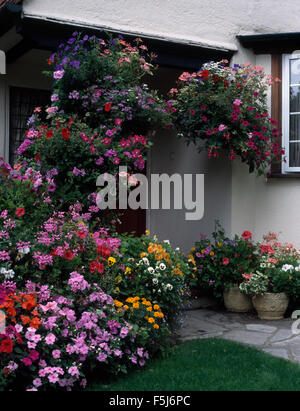 Bunte Sommerblumen in hängenden Körben und Töpfen vor Haus Stockfoto