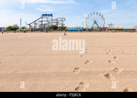 Englisch am Meer im Sommer. Fußabdrücke auf Skegness Strand führt zum Pleasure Beach Messegelände, Skegness, Lincolnshire, England, Großbritannien Stockfoto