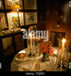 Kerzen in graviertes Glas Laternen und eine Vase mit rosa Rosen auf Tisch zum Abendessen in ein 80er Jahre Esszimmer set Stockfoto