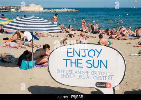 Warnung vor Sonnenbrand, mit Sonnencreme, UV, Gefahren, nicht schlafen am Strand von Barceloneta Strand, Stadtstrand Barcelona, Katalonien, Spanien. Stockfoto