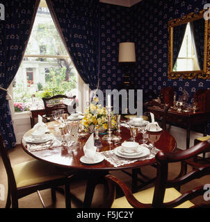 Dunkel blaue Tapete und passende Vorhänge Esszimmer mit Tisch für das Mittagessen der achtziger Jahre Stockfoto