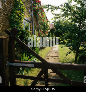 Blick über fünf bar Holztor des Pfads zum Landhaus mit Rosen an den Wänden Stockfoto