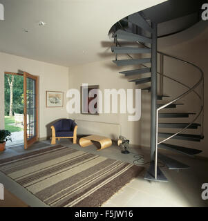 Grau gestreift Teppich in einer neunziger Jahre Halle mit einem Metall Wendeltreppe und blass Holzstuhl mit passenden Couchtisch Stockfoto