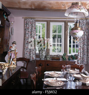 Tabelle Gruppe zum Mittagessen in der neunziger Jahre Cottage Esszimmer mit einer floralen viktorianischen Stil Messing und China Pendelleuchte Stockfoto