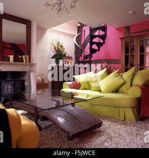 Lindgrün Sofa und ungewöhnliche Glas + Holz Couchtisch in einem Fuchsia pink neunziger Jahre Wohnzimmer mit Shag Haufen Teppich und spiralförmige Treppe Stockfoto