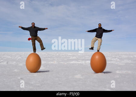 Optische Täuschung, zwei Männer stehen auf Eier, Salzsee Salar de Uyuni, Bolivien Stockfoto