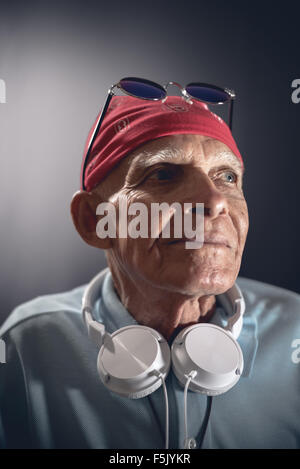 Alter Mann mit Kopfhörer, Kopftuch und Sonnenbrille. Stockfoto