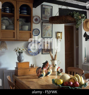 Kleine Glas-Front Kiefer Schrank an der Wand in einer neunziger Jahre Esszimmer mit Keramik Hühner auf einer alten Kiefer Tisch Stockfoto