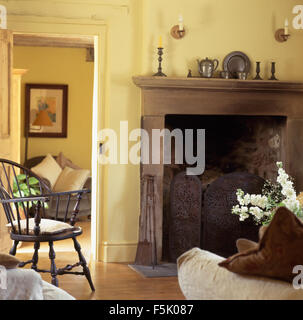 Schmiedeeisen Ofenschirm im Kamin im Wohnzimmer blass gelben Häuschen mit Antik Windsor Stuhl Stockfoto