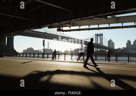 Zwei Chinatown Frauen ausüben, läuft ein Mann, ein anderer Mann geht beim betrachten die anderen entlang des East River Esplanade, New York Stockfoto