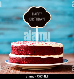 ein roter Samt-Kuchen mit einer Tafel in Form einer Sprechblase mit dem Text alles Gute zum Geburtstag, auf einem rustikalen Holztisch Stockfoto