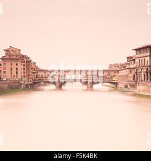 Ponte Vecchio mittelalterlichen Wahrzeichen am Fluss Arno in einer warmen Vintage Stimmung genommen durch eine 2 Minuten lange Belichtung Fotografie Stockfoto