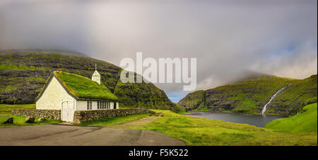 Panorama einer kleinen Kirche in Saksun, in der Nähe See und einem Wasserfall befindet sich auf der Insel Streymoy, Färöer-Inseln, Dänemark Stockfoto