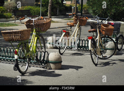 Drei Fahrräder mit Gepäcktaschen geparkt in aufgerollter Racks zur Verfügung gestellt in einem italienischen off Straße Parkanlage in jaunty Winkeln Stockfoto