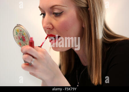 Junge hübsche Mädchen bewerben roten Lippenstift auf die Lippen in Worthing, West Sussex, UK. Stockfoto