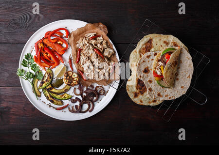 Fajita mit zog Schweinefleisch und Paprika. Tortillas, gegrillte Avocado, Zwiebeln mit Fleisch und Gemüse auf Teller serviert. Tex-Mex Stockfoto