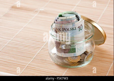 Geld sparen in Glas, polnische Zloty furled Bündel Banknoten und Münzen sammeln in den transparenten Behälter stehend... Stockfoto