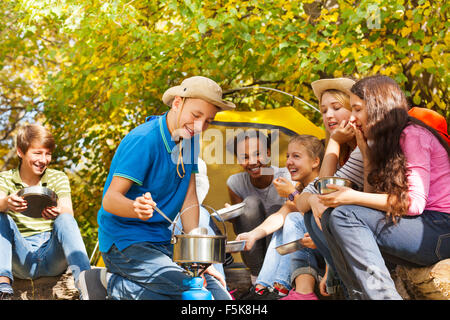Junge Köche Suppe im Topf für Freunde auf Campingplatz Stockfoto
