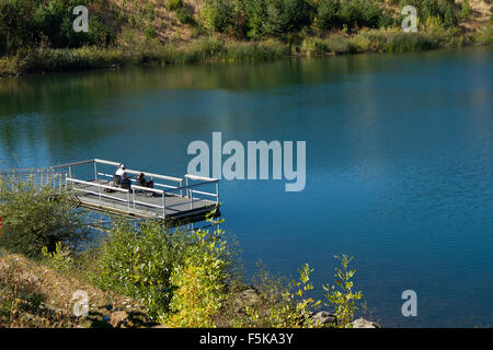 Ein älterer Mann und Enkelin Fischen in einem Teich geben die Idee, ein lustiges Ruhestand. Stockfoto