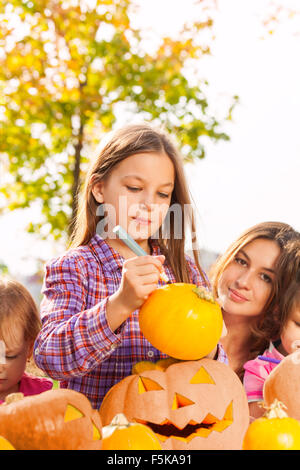 Porträt des kleinen Mädchens stützt sich auf Halloween-Kürbis Stockfoto