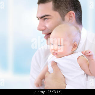 Porträt der glückliche junge Vater hält an Händen süß wenig kostbares Baby, gemeinsame Zeit zu Hause, liebevolle junge Familie Stockfoto