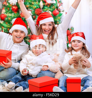 Porträt der glückliche Mutter mit drei fröhlichen Kinder genießen Geschenke vom Weihnachtsmann erhalten, Spaß in der Nähe von Christmas tree Stockfoto