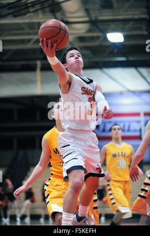 Spieler, der sich während eines Basketballspiels der High School vom Boden erhebt, um den Ball zum Reifen zu bringen. USA. Stockfoto